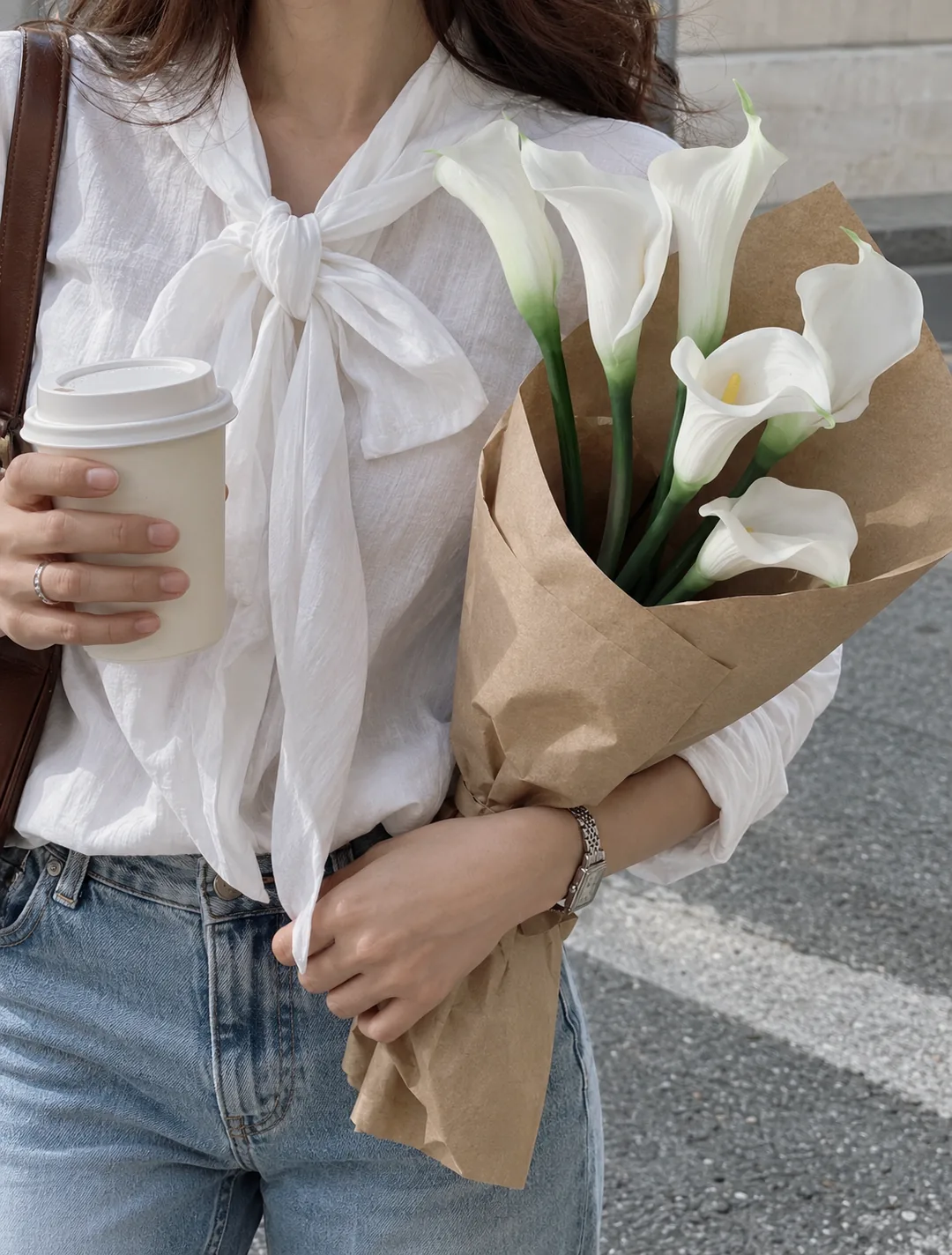 White calla lilies wrapped in kraft paper and held as a gift
